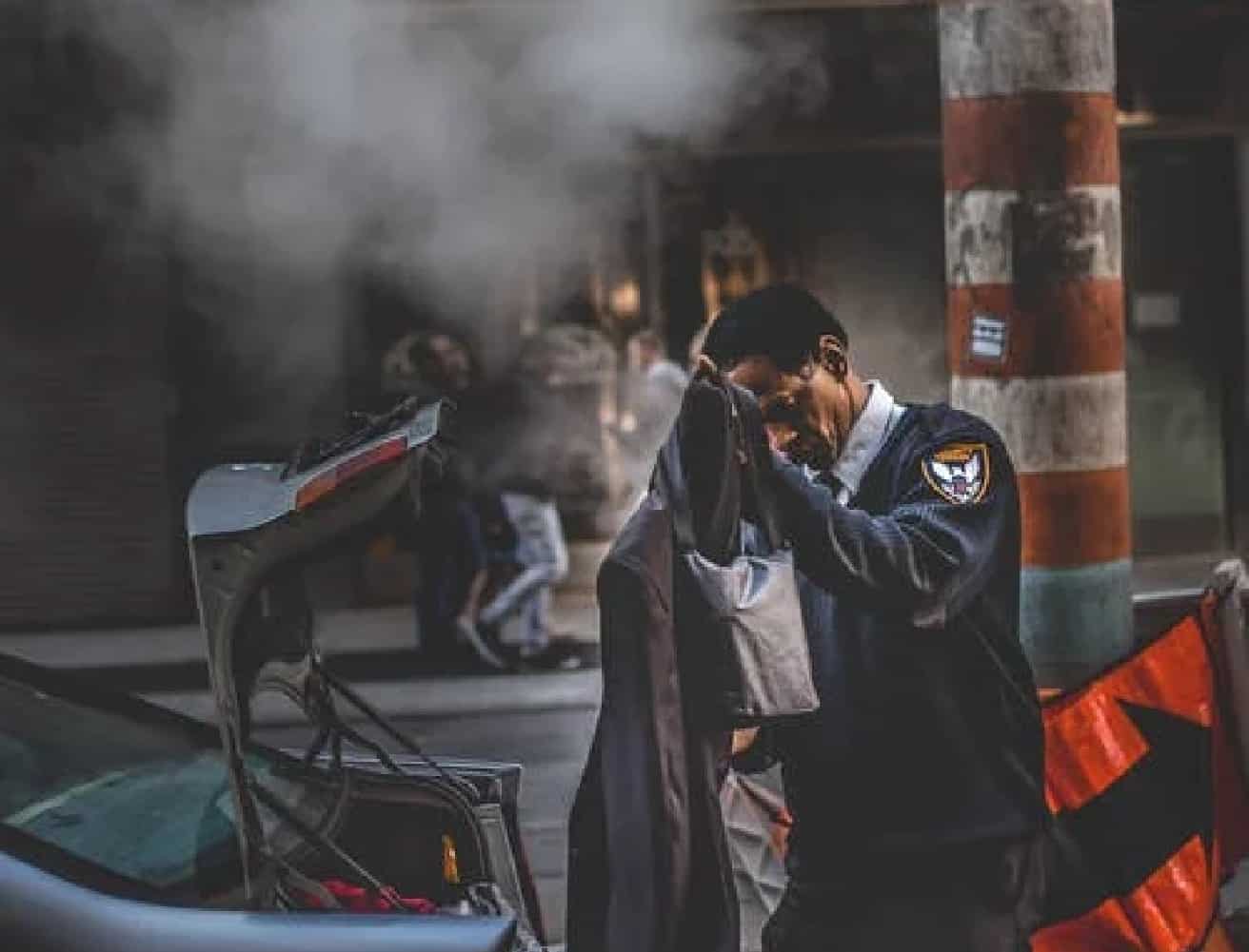 Police Officer Standing Behind The Car